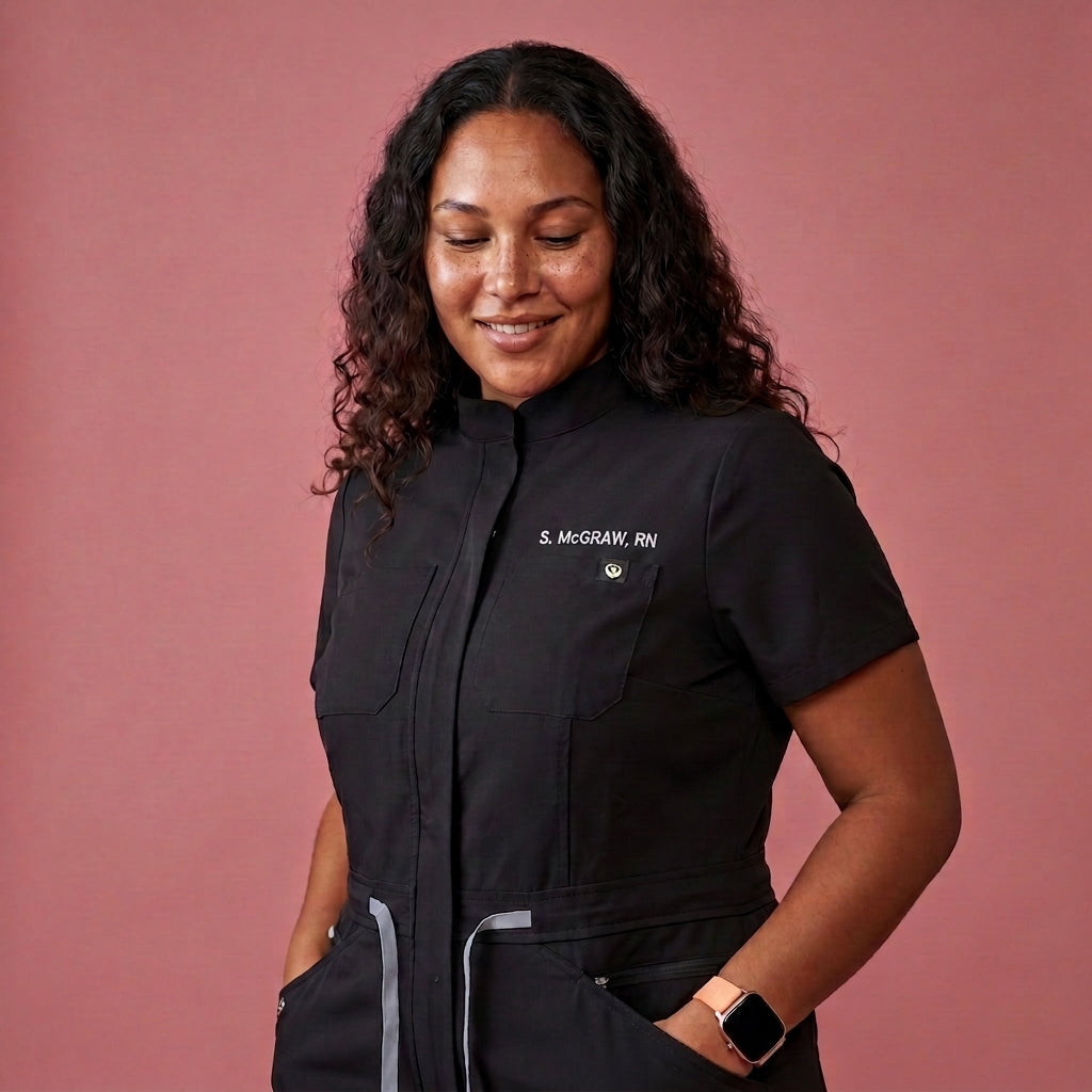 Woman wearing black scrub top with embroidered name text on chest