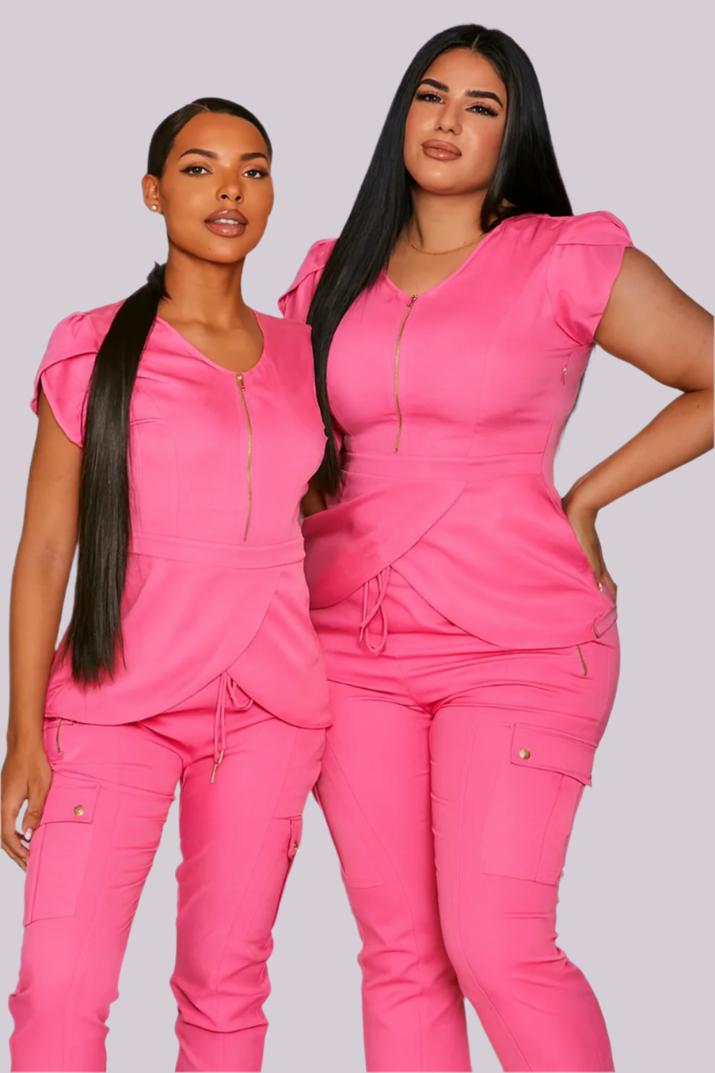 Two women wearing matching pink stylish scrubs against a white background