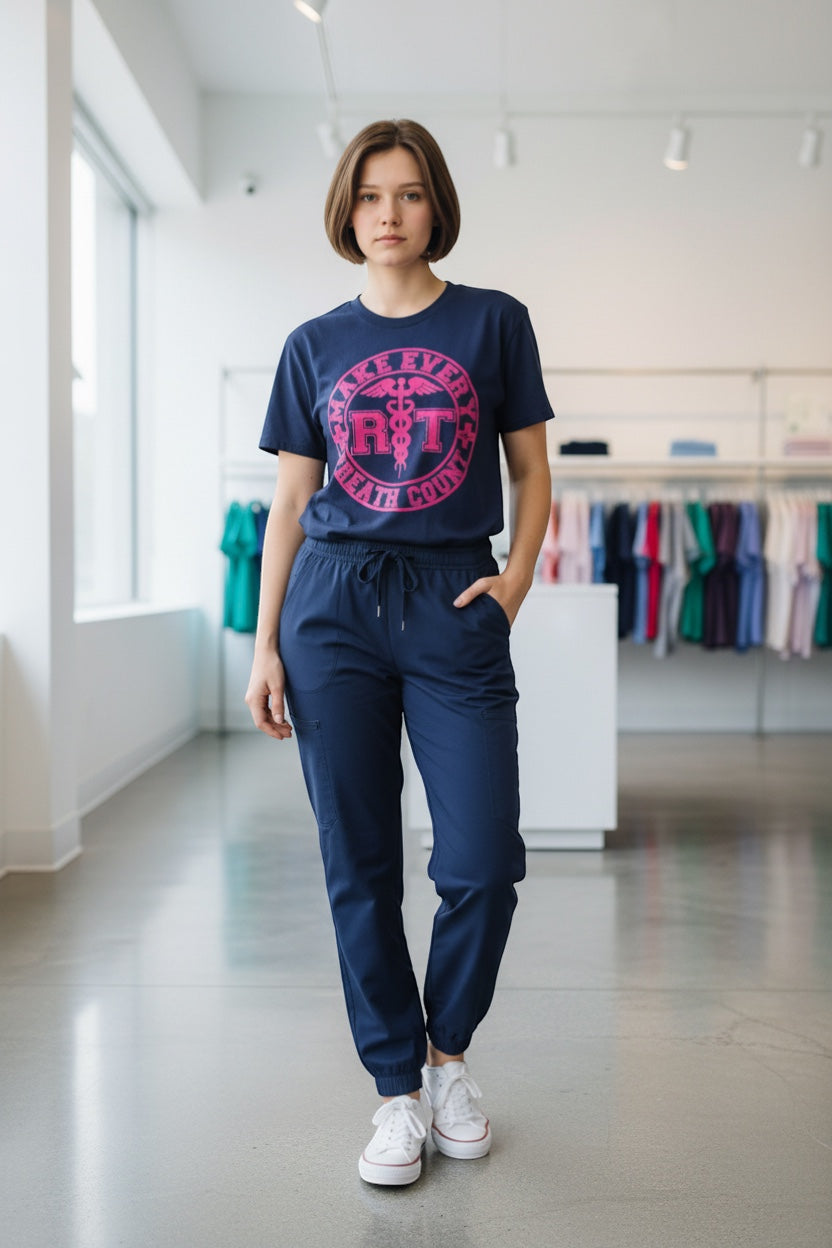Scrubs Galore Uniforms navy blue 100% cotton RT tee with pink 'Make Every Breath Count' graphic and caduceus symbol.