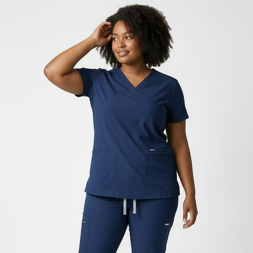 Scrubs Galore Uniforms navy blue CoreFlex scrub top with v-neck and two front pockets. Model is wearing matching scrub pants.