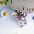 Scrubs Galore Uniforms nurse badge reel featuring two dolls wearing 'Saving Lives' shirts and carrying handbags. Clear acrylic with a retractable clip.